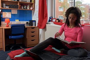Student reading on bed in accommodation room