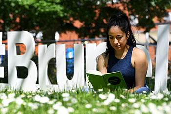Student studying outside infront of Brunel campus sign