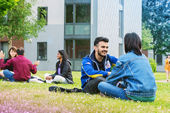 Students being social outside sitting on grass